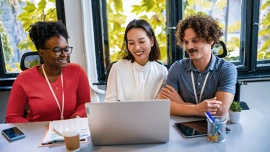 three young people working and looking at a laptop