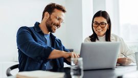 A man and a woman talk in front of the laptop