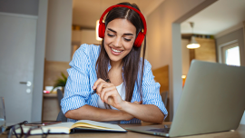 Girl studying on book and computer while listening to headphones